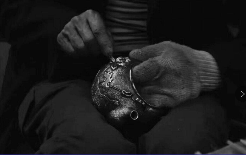 A Miao silver craftsperson is making a silver pot