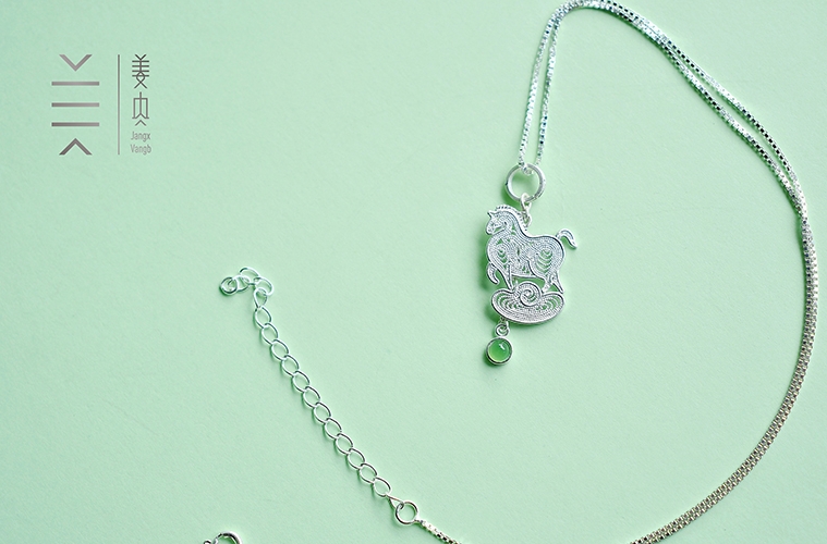 Silver horse pendant on green background