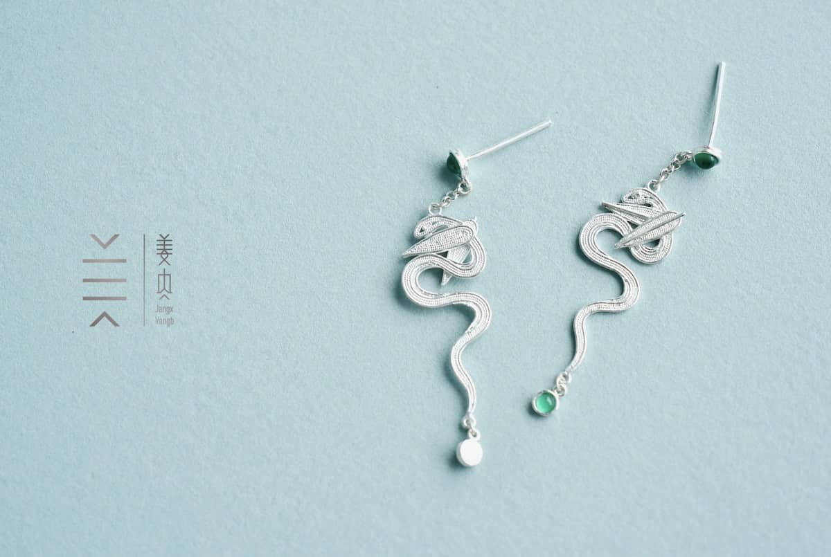 Elegant silver snake earrings with gemstones.