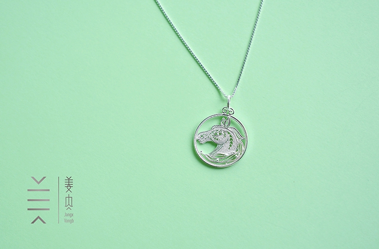 Silver horse pendant on green background